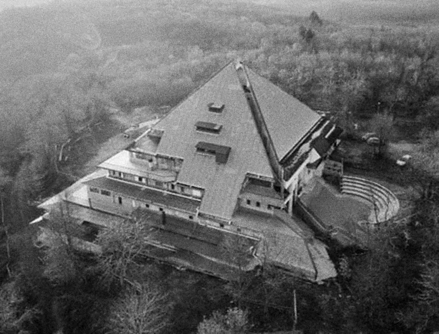 Aerial photograph of the base: a pyramid-roofed building among trees, with an amphitheatre beside it.